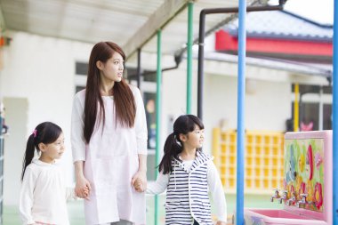 Japon kadın iki sevimli küçük kızla yürüyor ve el ele tutuşuyor. 