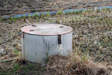 Kuru tarım arazisinde duran dairesel metal konteynır