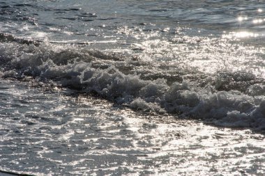 Sahildeki bir sahil cennetinde güneşli bir günde dalgalar zarif bir şekilde kıyıya vurur.