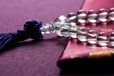 Dua boncukları ve bir dua kitabı. Mor bir bez üzerinde dinleniyor.