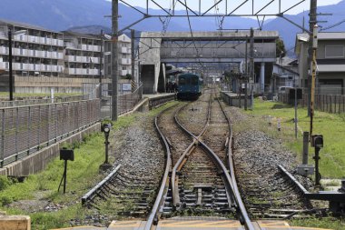 Bulutlu bir günde, binalarla çevrili farklı yolları olan bir istasyonun yanındaki tren rayları.