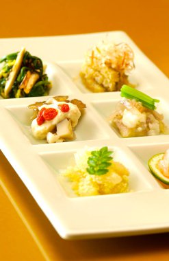 Beyaz seramik tepside sunulan renkli gurme tabakları.