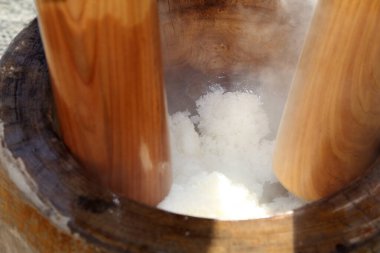 Buharda pişen pirinç ahşap havan içinde dövülüyor.