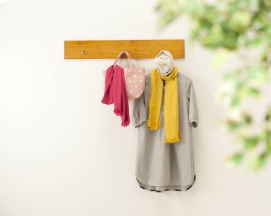 Üzerinde elbiseler ve aksesuarlar asılı olan ahşap askılık.