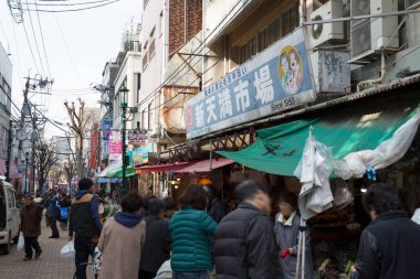 Tokyo, Japonya 'da binalarla dolu işlek bir cadde boyunca yürüyen insanlar.