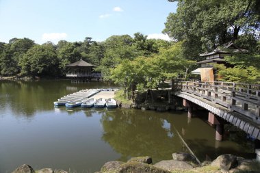 Tahta köprü rıhtımdaki kayıkların yakınındaki sakin göleti geçiyor.
