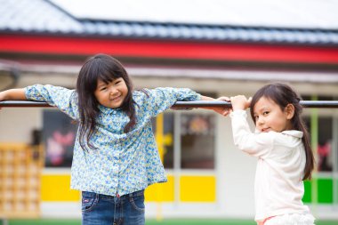 Parkta oynayan iki tatlı Asyalı küçük kız..