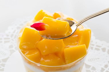 Arka planda kaşık olan mango tatlısı, kapat.