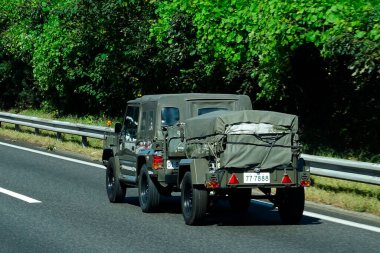 Çevresi yeşilliklerle çevrili askeri araç otoban boyunca ilerliyor.