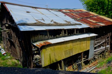 Paslı çatısı ve tahta duvarları olan harap bir bina.