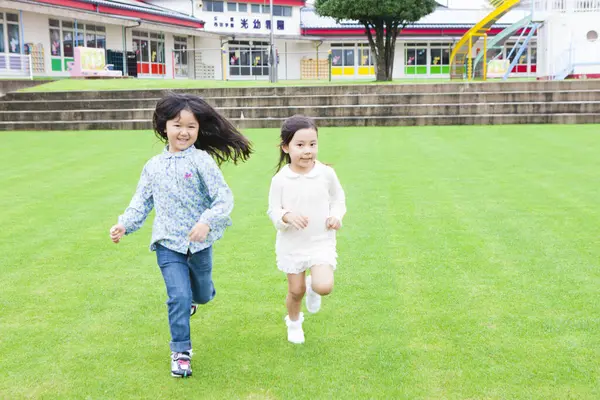 Porträtt Två Leende Asiatiska Små Flickor Som Springer Grönt Gräs — Stockfoto