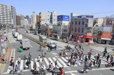 Tokyo, Japonya 'da caddelerde binaların önünden geçen bir kalabalık..
