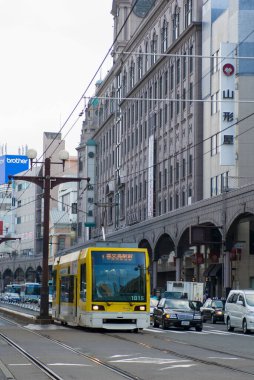 Yoldan geçen sarı tramvayla şehirde bir sokak fotoğrafı. 