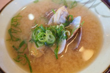 Taze midyelerle süslenmiş buharlı miso çorbası.