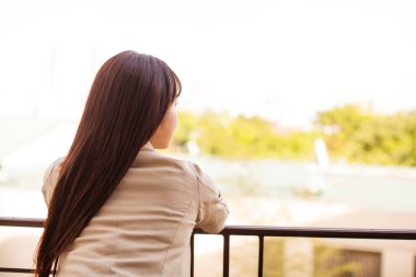 Balkonda uzun saçlı Asyalı bir kadının portresi.