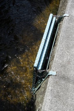 Metal yapı, akan suyun yakınındaki betonun üzerinde duruyor.