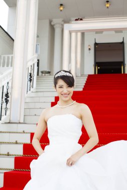 Merdivenlerde durup kameraya gülümseyen güzel gelinin portresi.