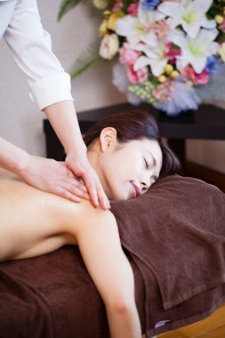 Genç Asyalı kadın güzellik salonunda sırt masajı yaptırıyor.