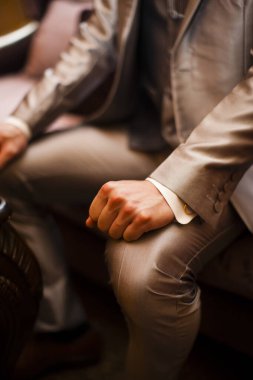 Şık takım elbiseli adam sandalyede oturuyor.