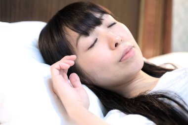 Asyalı kadın yatak odasında uyuyor. 