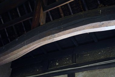 Eğri ahşap kiriş koyu kırsal tavan yapısını destekliyor