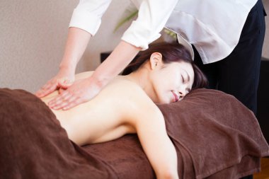 Genç Asyalı kadın güzellik salonunda sırt masajı yaptırıyor.