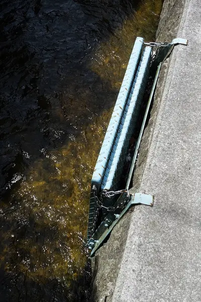 Metal yapı, akan suyun yakınındaki betonun üzerinde duruyor.