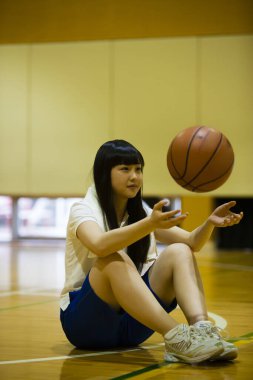 Japon kız basketbol sahasında oturuyor.