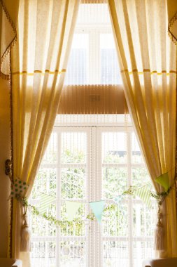 Güneş ışığı zarif perdelerin ve pencerelerin arasından akıyor.