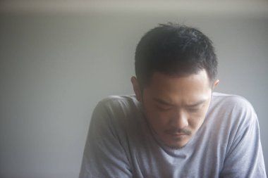 Asyalı üzgün bir adamın aşağı bakan portresi. 
