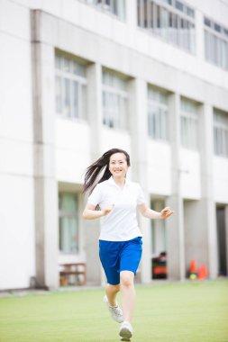 Spor giyimli genç Asyalı kadın dışarıda koşuyor. 