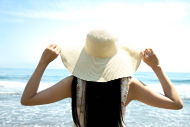 Şapkalı genç kadın denizde dinleniyor.