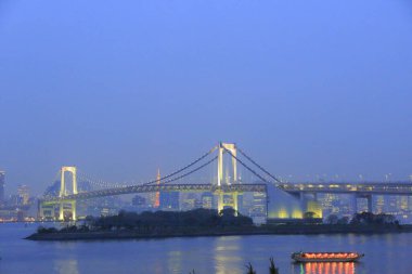 Aydınlatılmış Gökkuşağı Köprüsü 'nün gece görüntüsü, Tokyo Körfezi' nin kuzeyinden geçen bir asma köprü Shibaura İskelesi ile Minato, Tokyo, Japonya 'daki Odaiba liman bölgesi arasında.