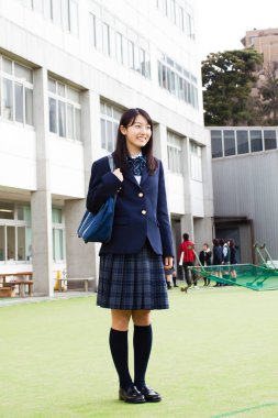 Okulun önünde üniforma giyen Asyalı kız.