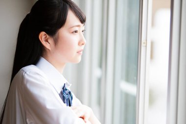 Asyalı okul öğrencisinin üniformalı portresi.