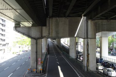 Şehirdeki yüksek beton yapının altındaki şehir yolu