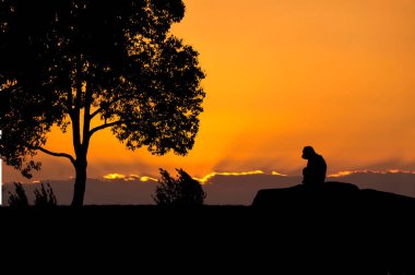 Günbatımı gökyüzü ile dağlarda dinlenen kişi 