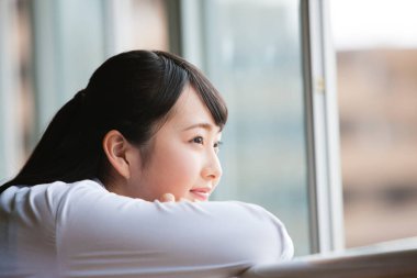 Pencereden dışarı bakan Asyalı bir kızın portresi.