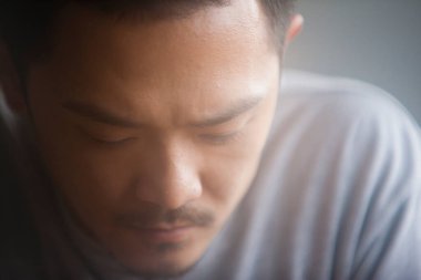 Asyalı üzgün bir adamın aşağı bakan portresi. 