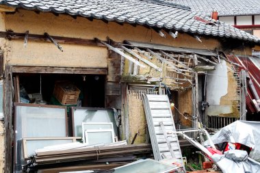 Binanın dış kısmı hasar görmüş. Enkaz ve kırık camlar görünüyor.