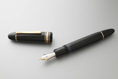 Gri yüzeyde eşleşen kepin yanında duran siyah dolmakalem.