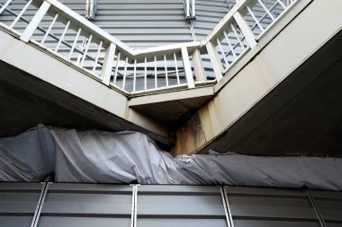 Metal bariyerin üstündeki açılı merdiven yıpranmış yüzeyleri gösteriyor.