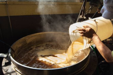 Adam büyük bir kasede sütten sıcak bir içecek hazırlıyor.