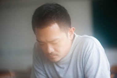 Asyalı üzgün bir adamın aşağı bakan portresi. 