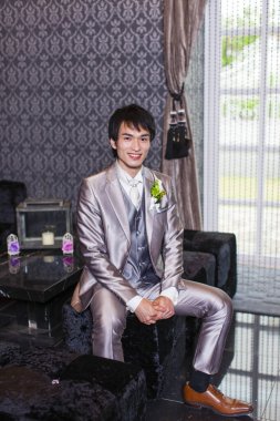 Kanepede oturan yakışıklı damadın portresi.