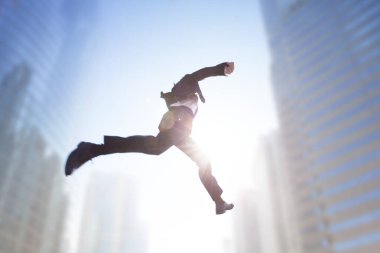 Şehir manzarasının üzerinden atlayan iş adamı