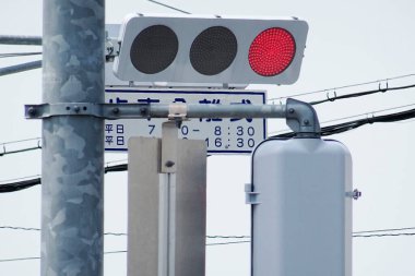 Traffic signal showing red light at an intersection with power lines in the background clipart