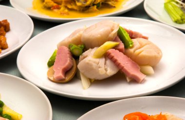 Zarif bir yemek ortamında beyaz tabakta servis edilen sebzeli lezzetli deniz ürünleri.