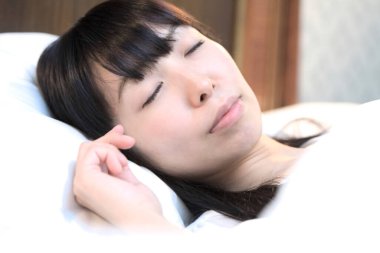 Asyalı kadın yatak odasında uyuyor. 
