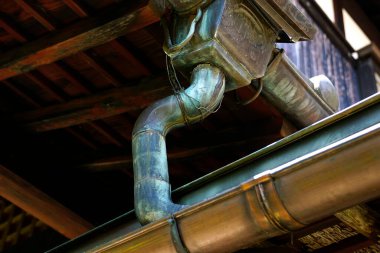 Rusty metal pipe extending from a wooden ceiling in an old building clipart